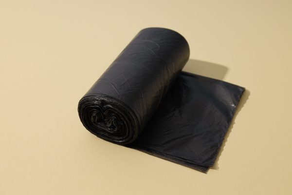Roll of black garbage bags on beige background
